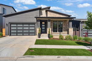View of front of house with stone siding, a porch, driveway, a garage, and a front yard