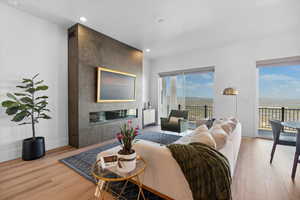 Living room with wood finished floors, baseboards, recessed lighting, and a large fireplace