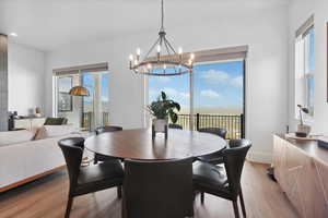 Dining area with light wood finished floors, a chandelier, plenty of natural light, and baseboards