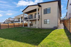 Rear view of house with a balcony, a patio area, and stucco siding