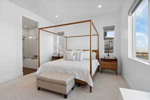 Bedroom featuring light carpet, recessed lighting, baseboards, and ensuite bath