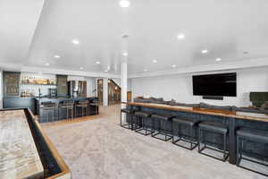 Indoor wet bar with stainless steel refrigerator with ice dispenser, light colored carpet, and recessed lighting