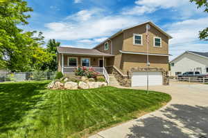View of front of house with stucco siding, covered porch, stone siding, concrete driveway, and a garage