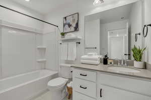 Full bath with toilet, vanity, tile patterned floors, and shower / washtub combination