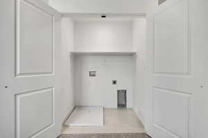 Washroom featuring hookup for a washing machine, electric dryer hookup, light tile patterned floors, and baseboards