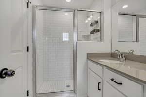 Primary suite featuring a glass enclosed shower, double vanity, and recessed lighting