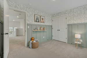 Bedroom with carpet flooring, a closet, wallpapered walls, and a decorative wall