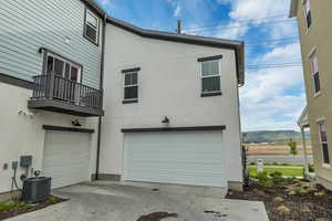 Back of property featuring a 2 car garage, central AC, stucco siding, and a mountain view