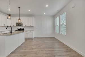 Kitchen featuring appliances with stainless steel finishes, a sink, tasteful backsplash, light wood-style flooring, and recessed lighting
