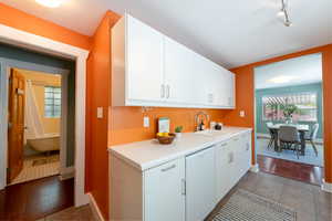 Kitchen with white dishwasher, a sink, light countertops, and white cabinetry