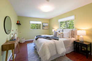 Bedroom with multiple windows, wood finished floors, and baseboards