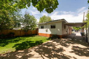 Rear view of property with concrete driveway and a carport