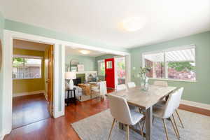 Dining space with healthy amount of natural light, wood finished floors, baseboards, and a fireplace