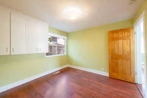 Spare room with baseboards, wood finished floors, and a textured ceiling