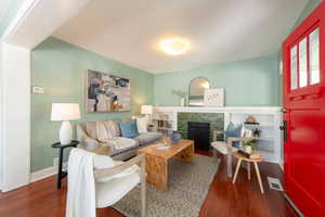 Living area with wood finished floors, a tiled fireplace, and baseboards