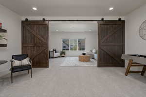 Living area featuring a barn door, carpet floors, recessed lighting, and baseboards