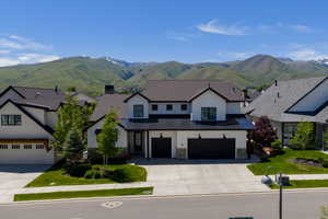 View of front of property featuring driveway, a standing seam roof, an attached garage, and a mountain view