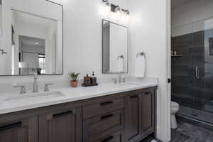 Full bathroom with double vanity, toilet, and a stall shower