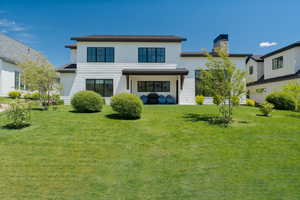 Back of house with a chimney and a lawn