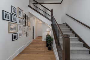 Stairway with wood finished floors, baseboards, and a high ceiling