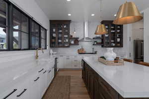 Kitchen with appliances with stainless steel finishes, dark brown cabinets, open shelves, wood finished floors, and backsplash