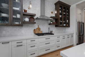 Kitchen with wall chimney range hood, stainless steel appliances, open shelves, and backsplash