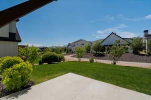 View of grassy yard with a patio area and a residential view