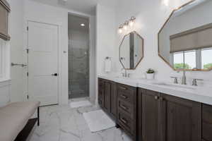 Bathroom with marble look tiles, double vanity, a marble finish shower, and recessed lighting