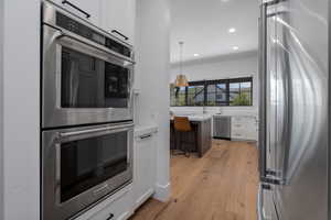 Kitchen featuring appliances with stainless steel finishes, white cabinetry, recessed lighting, light countertops, and light wood-type flooring
