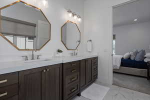 Ensuite bathroom with double vanity and marble finish flooring