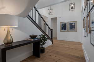 Foyer entrance with wood finished floors, baseboards, stairs, a towering ceiling, and a chandelier