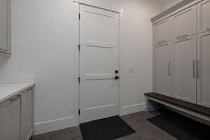 Mudroom featuring dark tile patterned floors and baseboards