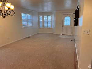 Formal dining/ formal living, Carpeted entryway with a chandelier, ornamental molding, and baseboards