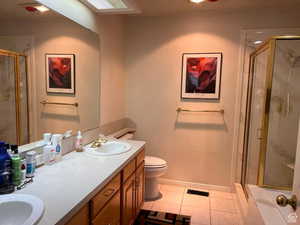 Full bathroom with double vanity, a shower stall, Sep tub/Sep Shower, toilet, and tile patterned floors