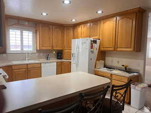 Kitchen featuring white appliances, a sink, plenty of natural light, light countertops, and recessed lighting