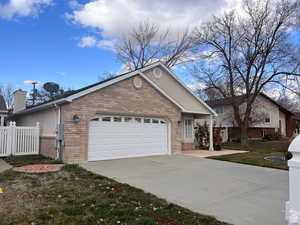 Ranch-style home with brick siding, concrete driveway, a garage, and a chimney
