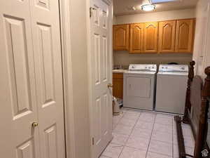 Laundry area featuring cabinet space, independent washer and dryer, and light tile patterned floors