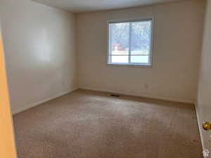 Spare room featuring carpet and baseboards