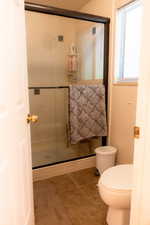 Bathroom with a stall shower, toilet, and tile patterned floors