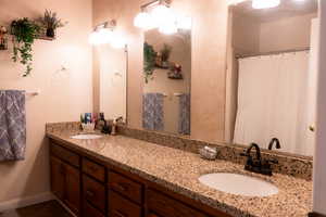 Full bath featuring double vanity, baseboards, and curtained shower