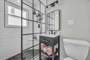 Full bathroom featuring toilet, a tile shower, and vanity