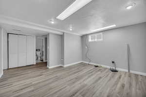 Below grade area featuring baseboards, light wood finished floors, and a textured ceiling