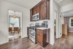 Kitchen featuring stainless steel appliances, dark wood-type flooring, light countertops, and baseboards