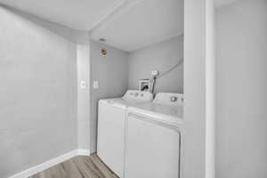 Washroom featuring independent washer and dryer, light wood-style floors, a textured ceiling, and baseboards
