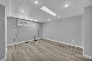 Basement featuring wood finished floors, baseboards, and a textured ceiling