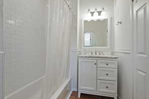 Full bathroom with vanity, shower / bathtub combination with curtain, and wainscoting
