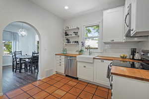 Kitchen featuring wooden counters, appliances with stainless steel finishes, arched walkways, a sink, and backsplash