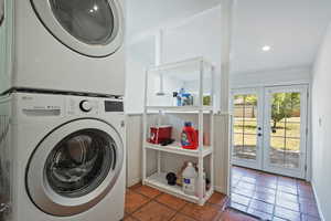 Laundry area with stacked washer / dryer, french doors, and tile patterned flooring