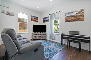 Living area with healthy amount of natural light, crown molding, hardwood / wood-style flooring, baseboards, and recessed lighting