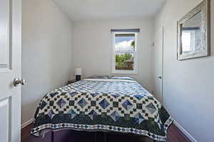 Bedroom featuring dark wood-style flooring and baseboards